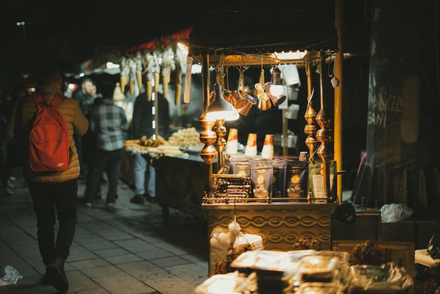 Night market with lit food stalls and people, creating a lively atmosphere.